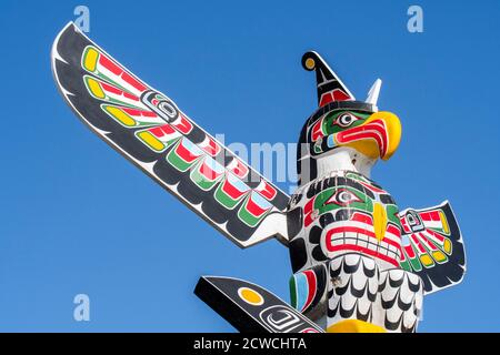 Mât de totem canadien sculpté en bois coloré montrant l'aigle contre le bleu ciel Banque D'Images