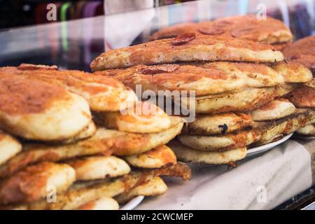 Cuisine de rue sicilienne, une montagne de 'sfincionello' de Palerme derrière un verre, (pizza douce typique avec sauce à l'oignon et anchois vendus dans la rue) Banque D'Images