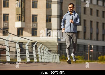 Jeune homme en vêtements de sport, jogging le long de la rue de la ville Banque D'Images