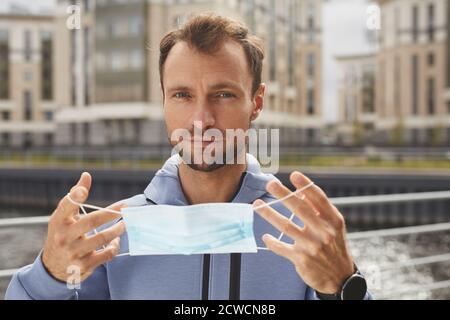 Portrait d'un jeune homme regardant l'appareil photo tout en portant une protection masque debout à l'extérieur Banque D'Images