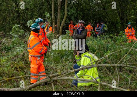 Denham, Royaume-Uni. 29 septembre 2020. Les gardes de sécurité HS2 entourent deux protecteurs d'arbre lorsqu'ils regardent les coupe-arbres abattre des arbres pour HS2 aujourd'hui dans le parc national de Denham, dans une zone où les protecteurs d'arbres HS2 Rebellion sont publics et à l'extérieur de la zone dans laquelle HS2 est autorisé à travailler. Environ 28 agents NET Enforcement et agents de sécurité HS2 ont empêché les protecteurs d'arbre de regarder l'évolution de la destruction des arbres. Les travaux de construction du HS2 mettent en péril 693 sites fauniques, 108 anciennes terres boisées et 33 ISSS. Crédit : Maureen McLean/Alay Live News Banque D'Images