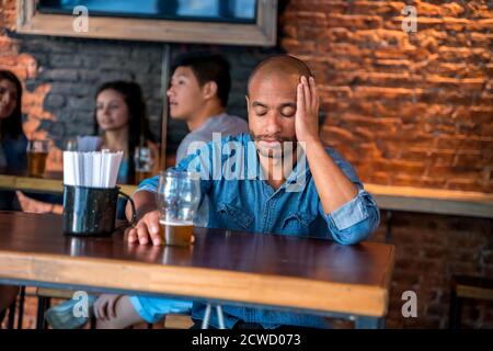 Un triste latin solitaire assis dans un bar ou un pub tout en buvant de la bière. Banque D'Images