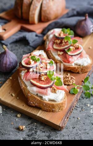 Sandwich avec tartiner au fromage de chèvre, prosciutto, figues et noix hachées Banque D'Images