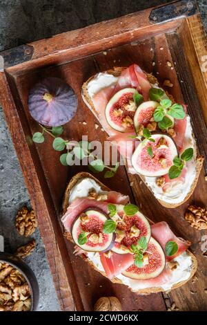 Sandwich avec tartiner au fromage de chèvre, prosciutto, figues et noix hachées Banque D'Images