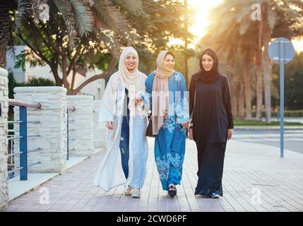 Trois femmes amies qui sortent à Dubaï. Les filles portant l'abaya traditionnelle des émirats arabes unis Banque D'Images