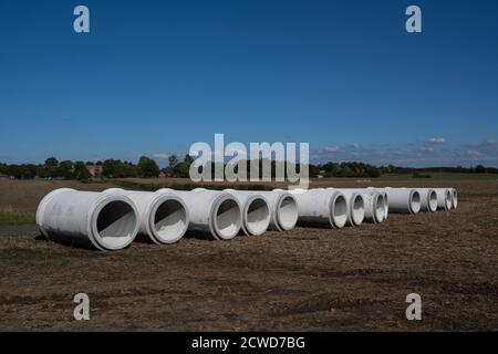 Grandes conduites d'eau en béton en rangée sur un champ sous un ciel bleu, site de construction d'un système d'égout de drainage contre les inondations, espace de copie, sel Banque D'Images