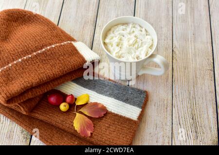 Toque et écharpe d'hiver chauds et délicieux chocolat chaud avec une crème à fouetter à déguster et à déguster en automne jours après les promenades dans les feuilles d'automne Banque D'Images