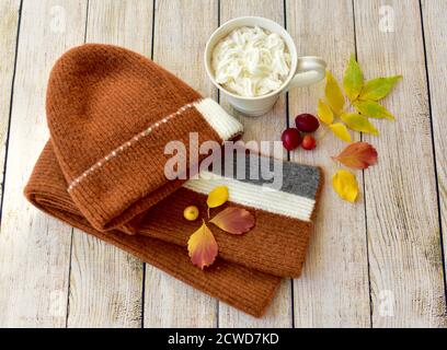 Toque et écharpe d'hiver chauds et délicieux chocolat chaud avec une crème à fouetter à déguster et à déguster en automne jours après les promenades dans les feuilles d'automne Banque D'Images