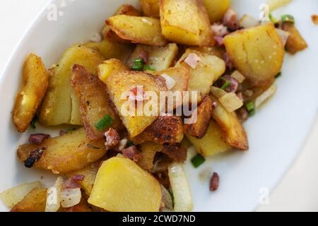 Pommes de terre frites dorées croustillantes avec oignons et bacon servies sur une assiette blanche, vue en grand angle depuis le dessus, mise au point sélectionnée, champ étroit Banque D'Images