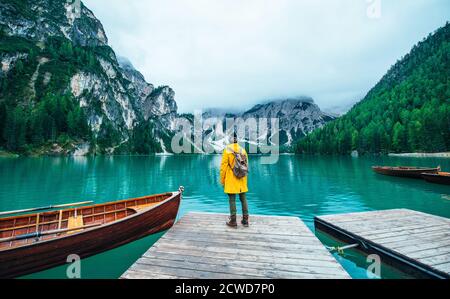 Histoires de montagne. Bon routard pour des vacances de Wanderlust. Homme avec un imperméable jaune debout devant le lac et appréciant la vue Banque D'Images