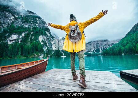 Histoires de montagne. Bon routard pour des vacances de Wanderlust. Homme avec un imperméable jaune debout devant le lac et appréciant la vue Banque D'Images