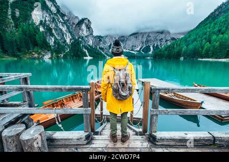 Histoires de montagne. Bon routard pour des vacances de Wanderlust. Homme avec un imperméable jaune debout devant le lac et appréciant la vue Banque D'Images