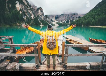 Histoires de montagne. Bon routard pour des vacances de Wanderlust. Homme avec un imperméable jaune debout devant le lac et appréciant la vue Banque D'Images