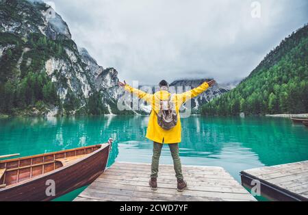 Histoires de montagne. Bon routard pour des vacances de Wanderlust. Homme avec un imperméable jaune debout devant le lac et appréciant la vue Banque D'Images