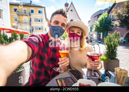 Couple heureux prenant un apéritif dans un café. Homme et femme en lune de miel voyage sur les dolomites italiens. Visite d'un village traditionnel dans une montagne Banque D'Images