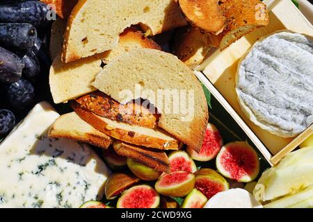 Un plateau de fromages gastronomiques avec du fromage de chèvre affiné et des figues, des pommes et des raisins frais Banque D'Images