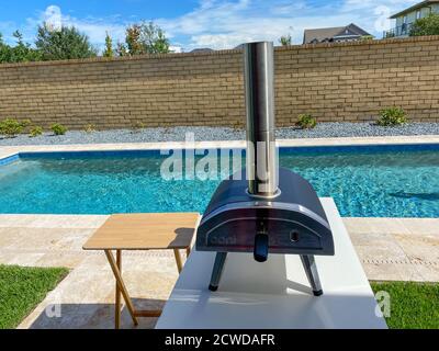 Orlando, FL/USA - 9/7/20: Un four à pizza au feu de bois OONI à côté d'une piscine dans l'arrière-cour d'une maison. Banque D'Images