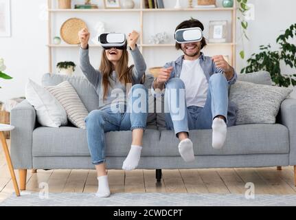 Jeune famille émotive jouant aux jeux vidéo dans le salon Banque D'Images