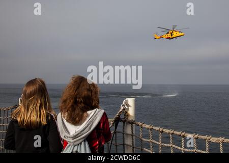 À bord d'un navire de guerre de la base des Forces canadiennes à Esquimalt, en Colombie-Britannique, une paire de femmes regardent une démonstration de recherche et de sauvetage d'un CH- Banque D'Images