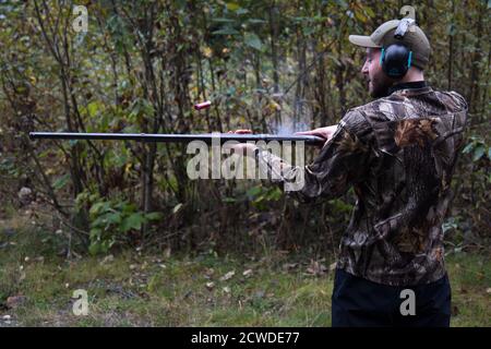 Squamish, Colombie-Britannique / Canada - 09/23/2018: Un homme portant une chemise de camouflage éjecte une carapace de fusil de chasse d'une vieille arme avec de la vapeur qui sort de la Banque D'Images