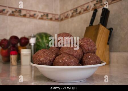 Boulettes de viande crues à l'intérieur de l'assiette dans la cuisine Banque D'Images