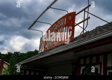 Une affiche ancienne, rouillée et cassée dans un magasin abandonné. Nuages orageux en arrière-plan Banque D'Images