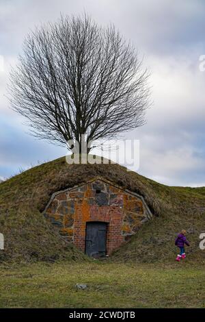 Structure construite sur le flanc d'une colline avec arbre et enfant grimpant. Banque D'Images