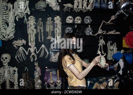 Femme en pandémie COVID-19 magasins de masques pour Halloween têtes de mort décorations À l'intérieur d'un magasin Spirit pour Halloween Banque D'Images