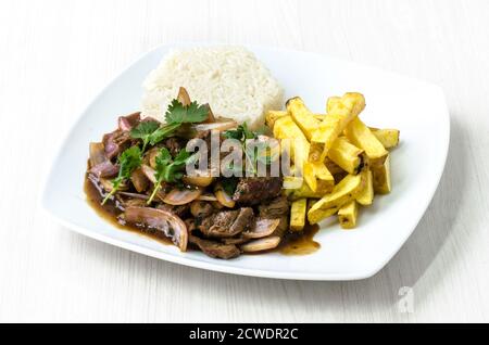 Plat appelé péruvienne Lomo Saltado faite de viande de boeuf, de tomates et oignons mélangés avec frites et servies avec du riz Banque D'Images