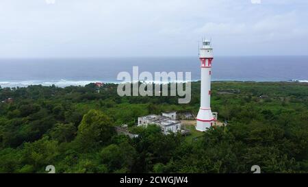 Phare de la tour blanche sur une grande île, vue de dessus. Colline de la forêt tropicale et tour du phare. Phare De Bolinao, Luzon, Philippines. Concept de vacances d'été et de voyage. Banque D'Images