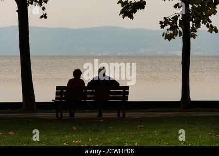 Deux vieux hommes regardent le paysage assis sur un banc au crépuscule Banque D'Images