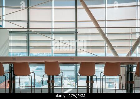 Rangée de chaises avec table de comptoir en bois sur vitre avec l'aéroport dans le salon Banque D'Images