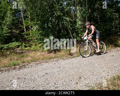 Radvanec, Tchéquie - 23 août 2020. L'événement de triathlon Samuel XC. Le conducteur MTB en casque rouge noir et en jersey noir maintient les freins devant le t droit Banque D'Images