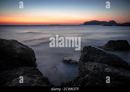 Coucher de soleil sur la côte rocheuse de Crète , avec marées qui coulent en arrière-plan. Banque D'Images