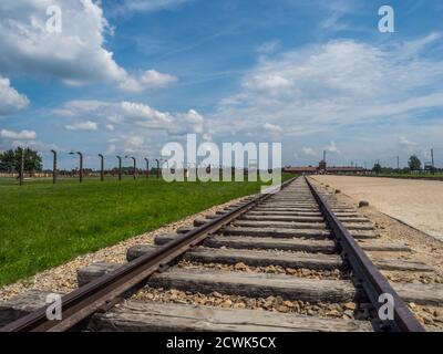 Oświęcim, Pologne - Juin 05, 2019 : les voies de chemin de fer et d'une clôture électrique à Auschwitz Birkenau Camp de concentration. Camp d'extermination des juifs. L'Europe Banque D'Images