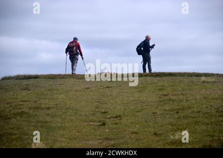 Deux hommes marchant et se tenant près de la pile de pierres sur le sommet Cairn du Wainwright 'Wandope' dans le parc national de Lake District, Cumbria. ROYAUME-UNI. Banque D'Images