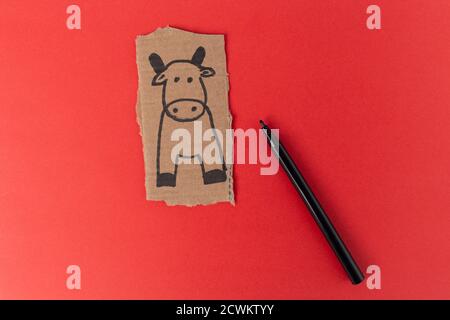 Vache artisanale en carton, Comment faire un taureau ou un boeuf à la maison. Projet d'art pour enfants. Concept DIY. Fabrication du jouet sur le rouge. Instructions détaillées sur la photo. Ste Banque D'Images