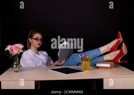 Jeune enseignante avec ses feets sur la table. Banque D'Images