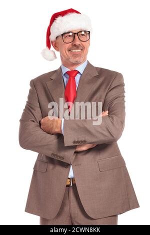 le vieux père noël souriant homme d'affaires debout avec les mains repliées regarde loin et sourit sur fond blanc Banque D'Images