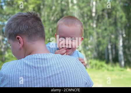 petit frère assis sur les mains du frère aîné et montrant sa dent. petit garçon blond embrassant son frère. togetherness et concept de soutien familial. soins des dents de bébé. Banque D'Images