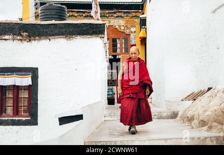 Monastère de Thiksay dans le village de Thiksey, Inde – 20 août 2016 : un moine âgé passe par le monastère élevé dans la kasaya rouge traditionnelle du village de Thiksey, I Banque D'Images