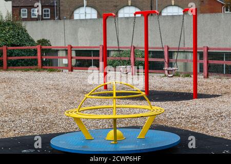 Une aire de jeux pour enfants ou un parc vide montrant un rond-point et balançoires Banque D'Images