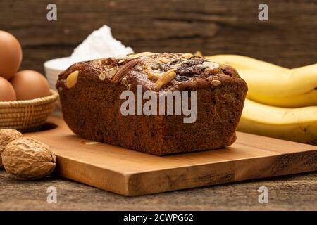 Gros plan les gâteaux Banana sont placés sur un plateau en bois sur une table en bois, avec des bananes, des œufs, de la farine comme arrière-plan. Banque D'Images