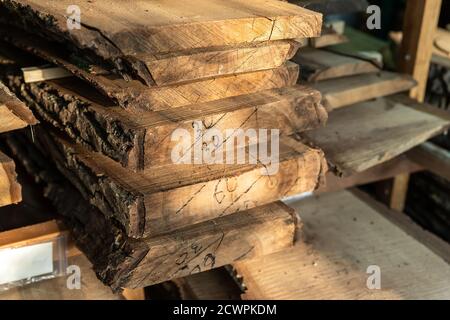 Pieu de dalle de bois scié à séchage d'air sous la verrière à la maison préparé pour le bricolage de menuiserie. Magasin de hangar à bois à la cour de la maison. Matériau en bois Banque D'Images