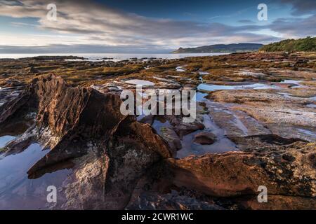 Rochers de grès et littoral au lever du soleil près de Corrie, île d'Arran, Écosse, Royaume-Uni Banque D'Images