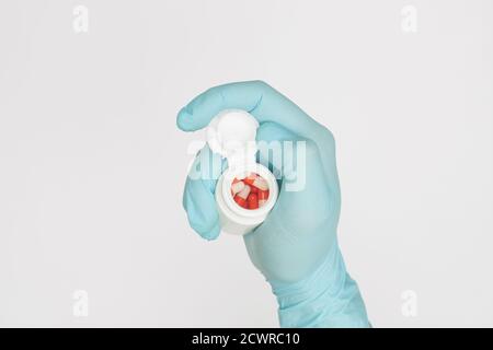 main dans le gant avec un pot de capsules sur fond blanc covid-19 concept de prévention du coronavirus pose plate Banque D'Images