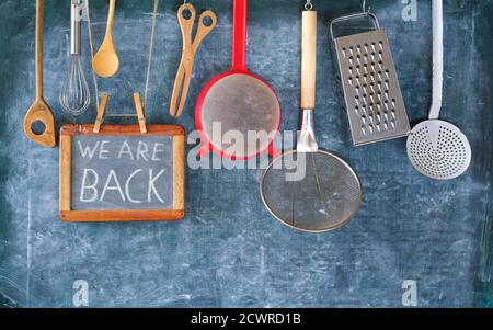 Restaurant annonçant la réouverture après le verrouillage du virus de la couronne, ustensiles de cuisine et message nous sommes de retour sur le tableau noir, de retour à la gastronomie des affaires Banque D'Images