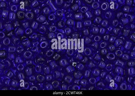 Fond de perles de semence en verre bleu, perles transparentes sur fond blanc. Arrière-plan ou texture des perles. Gros plan, macro,. Créer collier de perles ou str Banque D'Images