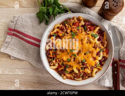 Bol de mac Chili avec cheddar sur une table rustique en bois. Vue de dessus avec espace de copie Banque D'Images