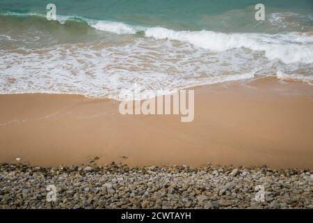 vue depuis le sommet des vagues turquoise le sable jaune et les galets de plage Banque D'Images